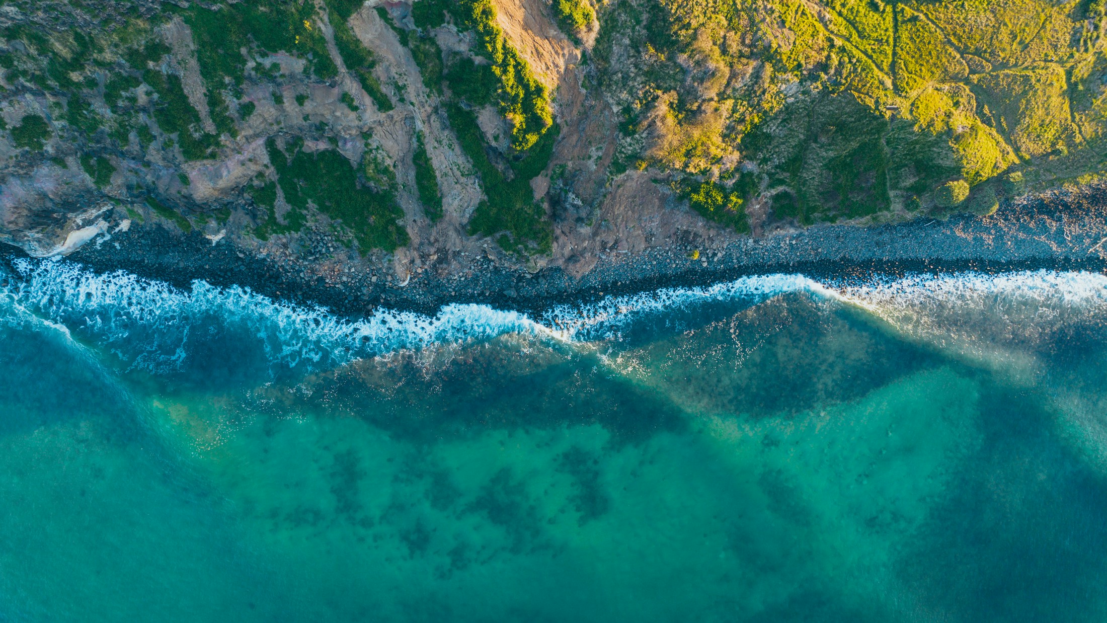 Waves breaking along a wild, green coastline